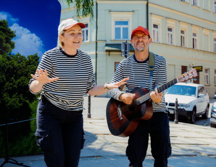 Kobieta się uśmiecha, a mężczyzna gra na gitarze.