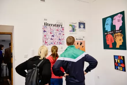 Dwie kobiety i mężczyzna oglądają wystawę. 