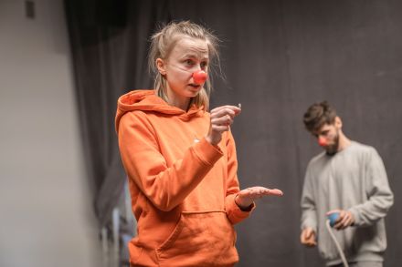 Kobieta z noskiem clowna trzyma w palcach mały pyłek.