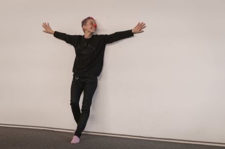 Kobieta z nosem clowna opiera się o ścianę.