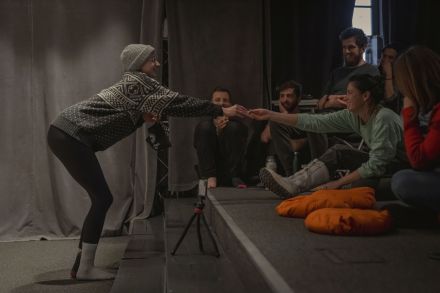 Kobieta przebrana za babcię rozdaje publiczności cukierki.