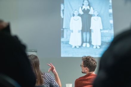 Uczestnicy oglądają czarno-białe zdjęcia zeskanowane i wyświetlane na prezentacji.