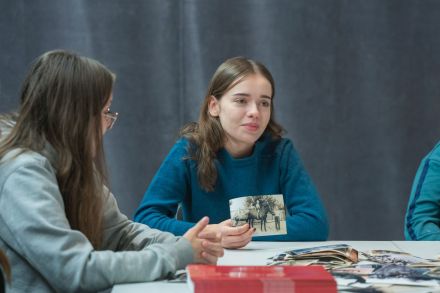 Dwie dziewczyny siedzą przy stole i rozmawiają o fotografii.