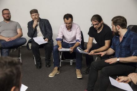 Zdjęcie ukazuje uczestników zajęć pochylonych nad tekstami wydrukowanymi na kartkach.