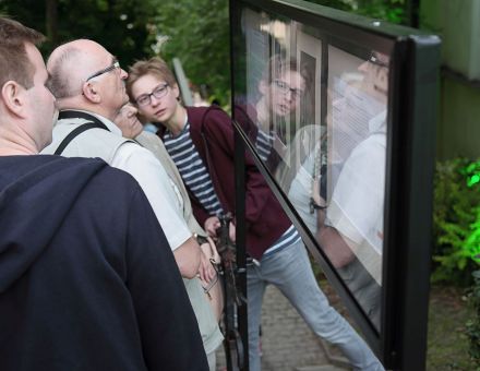 Trzech mężczyzn ogląda wystawę.