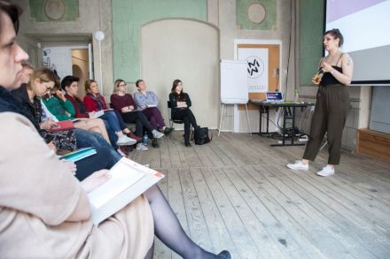 Uczestnicy szkolenia Inkubatora Kultury dotyczących zagadnień \"Social Media\" patrzą w stronę prowadzącej stojącej przed ekranem rzutnika.