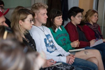 Zdjęcie przedstawia zbliżenie na część uczestników warsztatów znajdujących się w pierwszym rzędzie. Wszyscy siedzą na krzesłach i patrzą przed siebie.