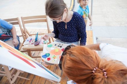 Zdjęcie zrobione lekko z góry, widać kobietę, która zastanawia się jaki kolor farby użyć.