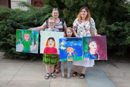 Na zdjęciu dwie pary warsztatowe stoją obok siebie ze swoimi obrazami. Podobizny są wykonane bardzo starannie. Obrazy są kolorowe, wyraziste, pełne detali.