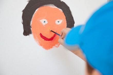 Zbliżenie na malowaną przez chłopca twarz kobiety.