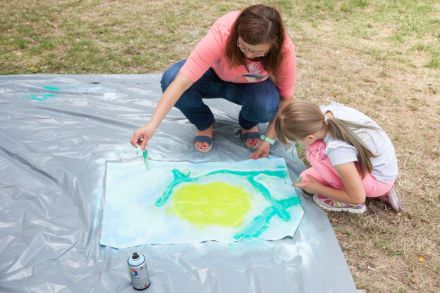 Na zdjęciu kobieta razem z dziewczynką tworzą dzieło na płótnie.