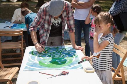 Na zdjęciu mężczyzna pomaga dziewczynce rysować ośmiornicę.