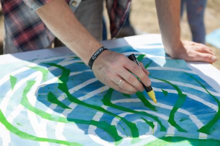 Zbliżenie na męskie dłonie, trzymające żółty marker. Mężczyzna dorysowuje obok ramion ośmiornicy linie, dzięki którym obraz staje się dynamiczny. Powstaje wrażenie, że ośmiornica się rusza.