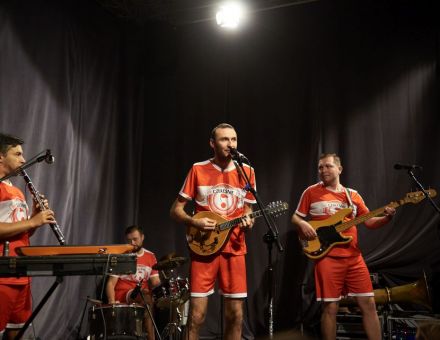 Koncert zespołu Czereśnie. Czterech muzyków na scenie w piłkarskich strojach.