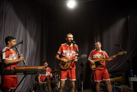 Koncert zespołu Czereśnie. Czterech muzyków na scenie w piłkarskich strojach.