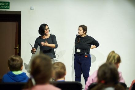 Na zdjęciu widzimy duet aktorski czyli koordynatorkę projektu oraz koordynatorkę Nocy Kultury, która stoi obok prowadzącej i mówi do dzieci.
