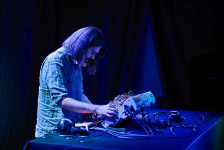 Na zdjęciu artysta wytwarza dźwięki na urządzeniu elektronicznym