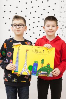 Warsztat architektoniczny  [warsztat dla dzieci w ramach Zimowej Majsterni. Na zdjęciu dwóch chłopców trzymających makietę miasta. Praca wielokolorowa. Dużo budynków stojących obok siebie. Na górze napis miasto wolności]