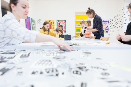 Na zdjęciu dzieci siedzące przy stole, na którym znajduje się mnóstwo kartek.