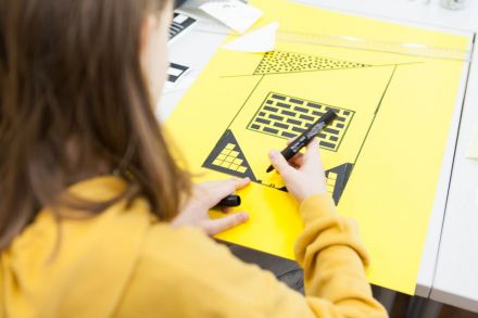 Zbliżenie na uczestniczkę, która wykonuje plakat architektoniczny związany z ulubionym budynkiem.