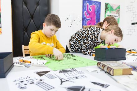 Na zdjęciu troje dzieci podczas pracy nad swoimi plakatami.