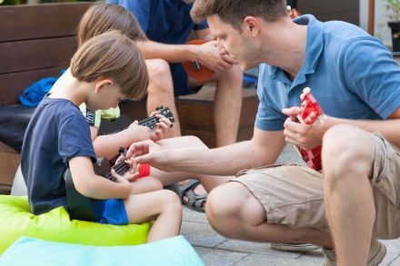 Prowadzący pokazuje chłopcu jak wykonać chwyt na ululele.