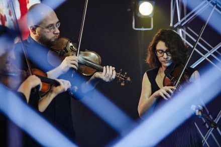 Zdjecie zza kratownic. Na zdjęciu skrzypek i skrzypaczka.