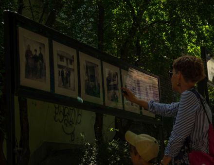 Mężczyzna ogląda wystawę. Dotyka jednego ze zdjęć.