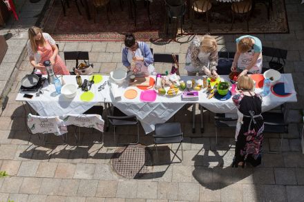 Uczestnicy warsztatów stojący dookoła stołu. Zdjęcie z lotu ptaka.