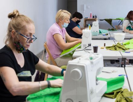 Kobiety zszywają materiały na maszynach.