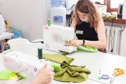 Dwie kobiety siedzące naprzeciw siebie szyją na maszynach.