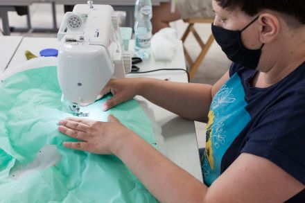 Zbliżenie na ręce kobiety, która szyje na maszynie.