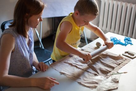 Chłopiec rozwałkowuje glinę.