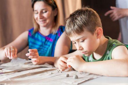 Chłopiec kręci kulki z gliny.