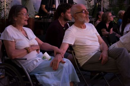 Starsze małżeństwo siedzące na koncercie . Mężczyzna trzyma rękę na kolanie kobiety.