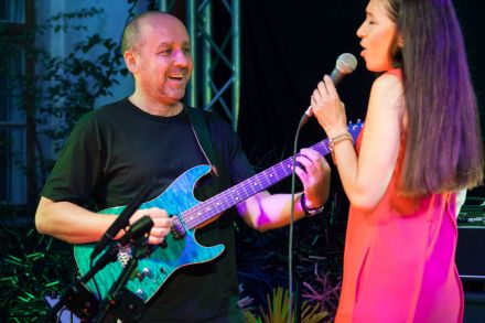 Zbliżenie na wokalistę i gitarzystę. Uśmiechają się do siebie.