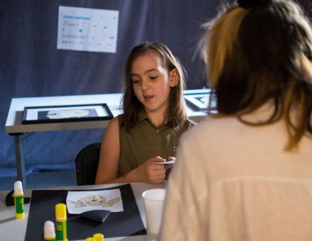 Dziewczynka wraz z prowadzącą zajęcia pracuje nad swoją wyklejanką.