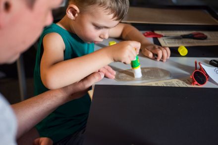 Chłopiec z klejem w ręce pracuje nad wyklejanką.