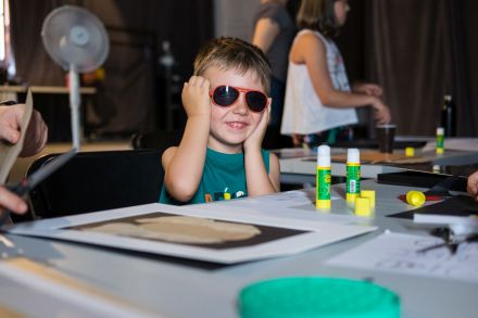 Chłopiec w okularach przeciwsłonecznych uśmiecha się do obiektywu.