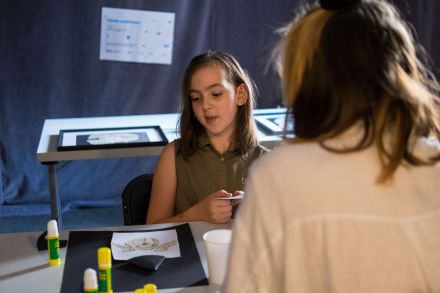 Dziewczynka wraz z prowadzącą zajęcia pracuje nad swoją wyklejanką.