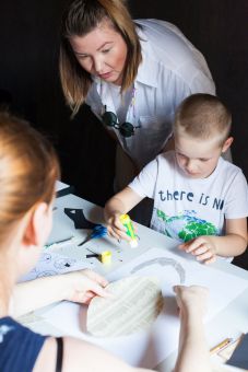 Chłopiec przykleja głowę psa do kartki.