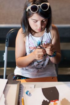 Dziewczynka wycina figurę z kolorowego papieru, która będzie fragmentem jej obrazka.