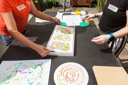 Zbliżenie na ręce prowadzącej, która oprawia w ramki obrazki dzieci.