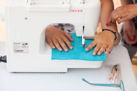 Zbliżenie na maszynę do szycia, na której dziewczyna kończy robić strim toy.