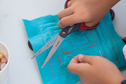 Zbliżenie na dłonie i nożyczki. Dziewczyna obcina ostatnie wystające nitki.