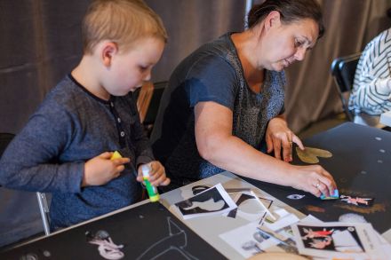 Zbliżenie na chłopca z klejem w ręce. Obok niego prowadząca rozsypuje brokat po kartce.