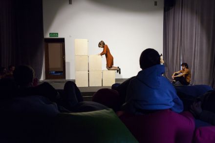 Scena. Aktorka wspina się po schodkach zrobionych z kartonów.