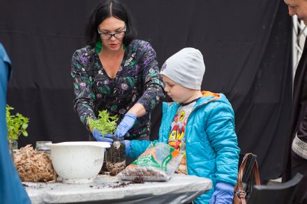 Chłopiec i prowadząca przesadzają kwiaty.