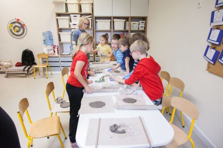 Dzieci stoją przy stole. Wybierają foremki.