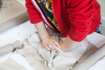 Zbliżenie na dłonie chłopca, który ugniata glinę.